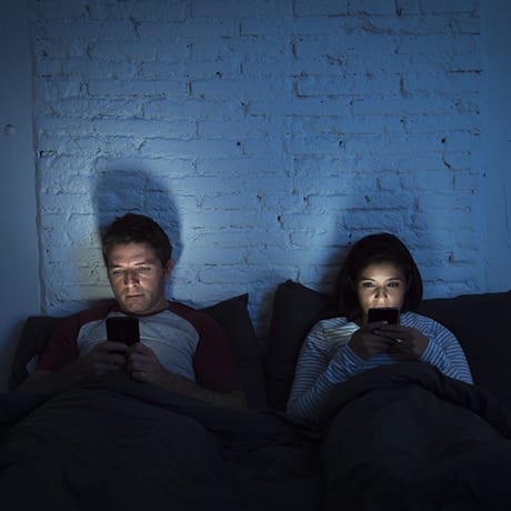 Couple regardant leurs smarphones au lit