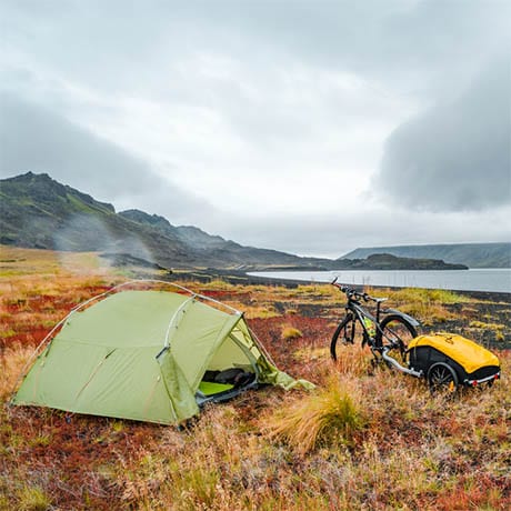 A tent with a beautiful and wild landscape with a bicycle in front