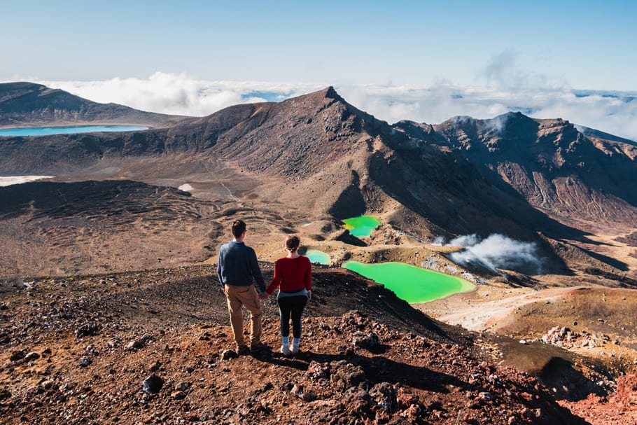 Travelling couple holding hands at the top of a volcano