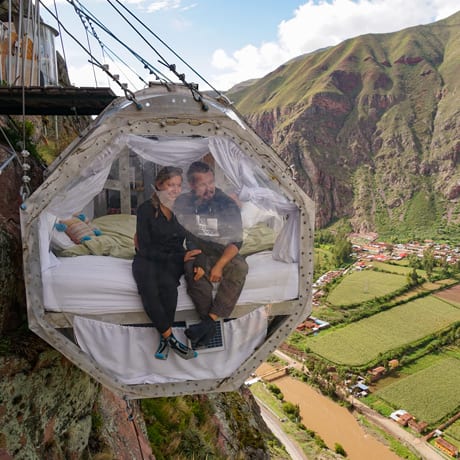 A travelling couple in a glass capsule suspended 1,200 feet up a mountainside