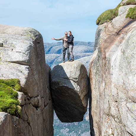 A travelling couple stands on a hanging rock